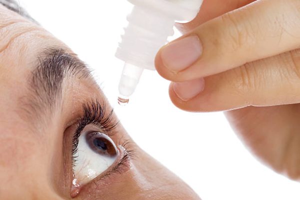 man applying eyedroppers, close up